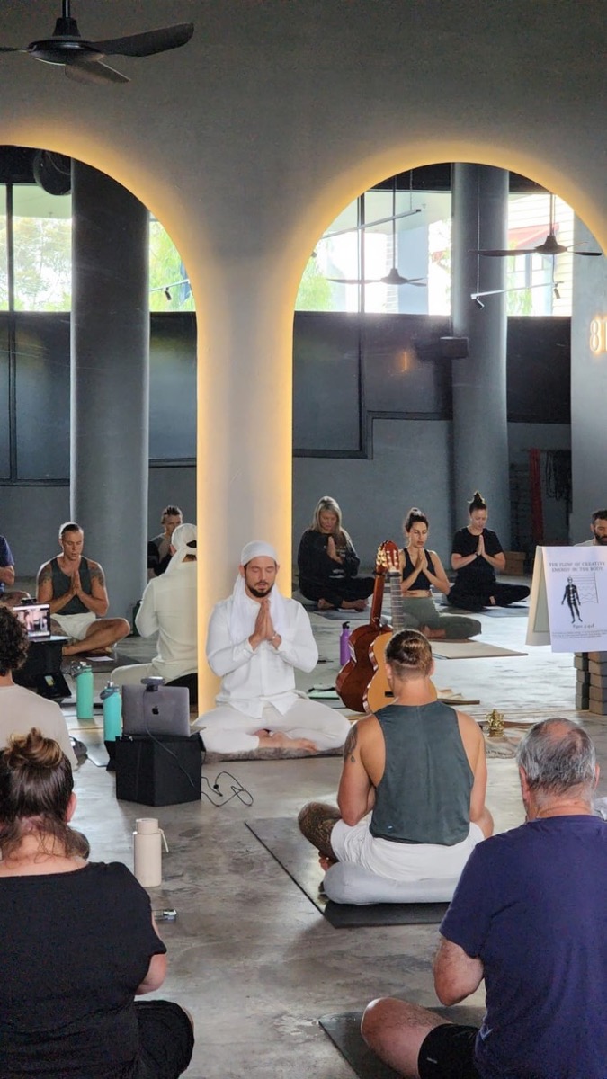 A group sitting in meditation beneath lit archways