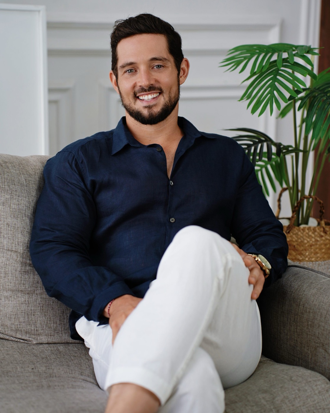 Zach seated, smiling, beside a palm